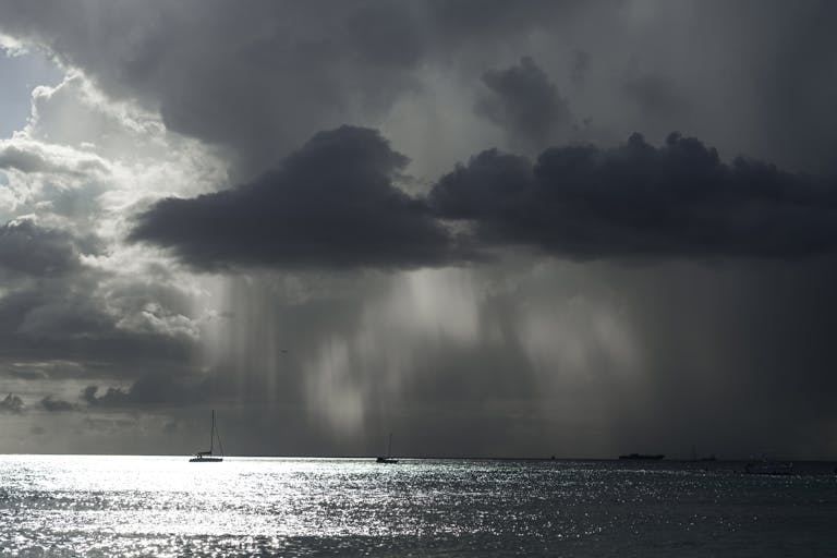 A powerful seascape featuring storm clouds, boats, and a shimmering sea, showcasing nature's drama.