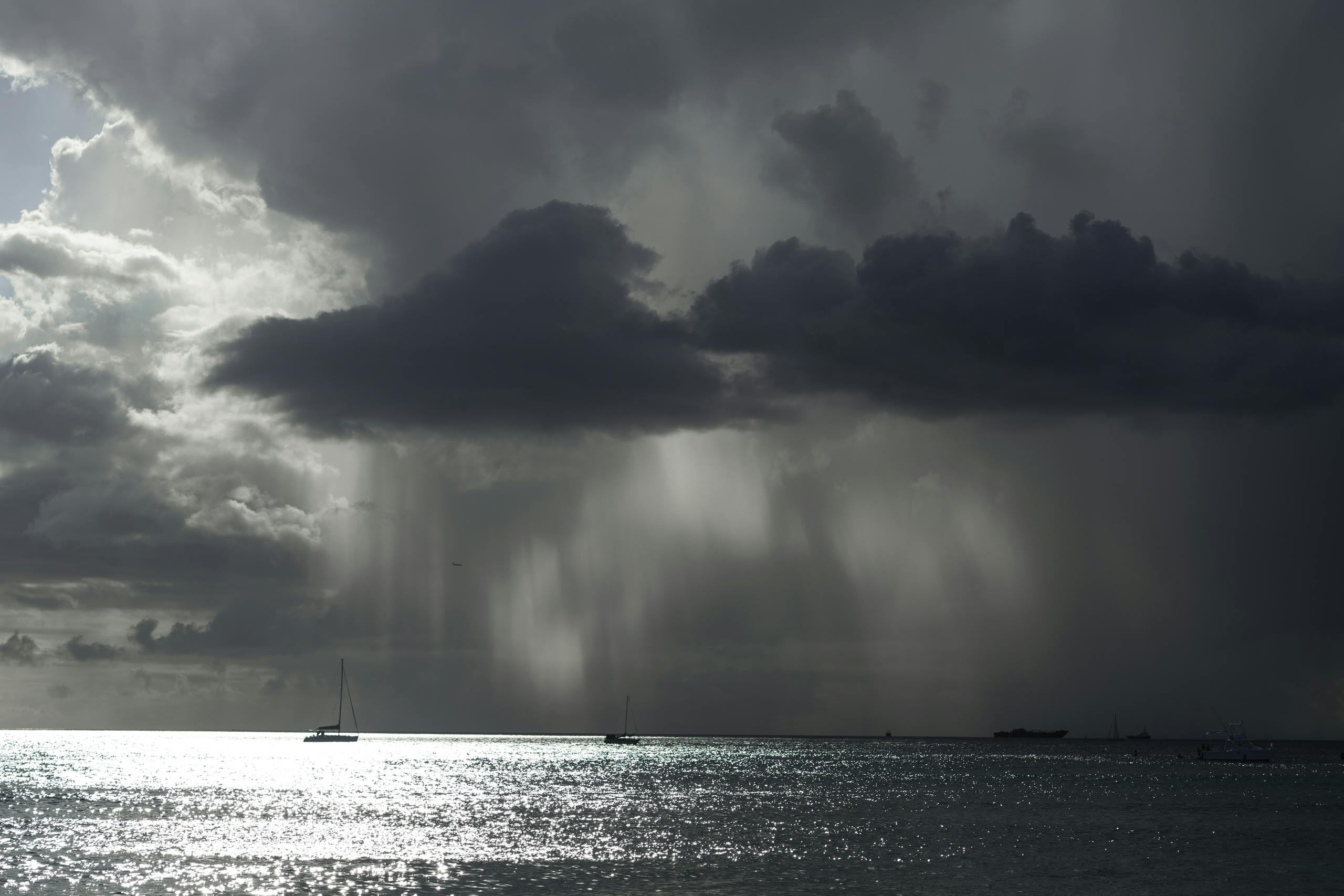 A powerful seascape featuring storm clouds, boats, and a shimmering sea, showcasing nature's drama.